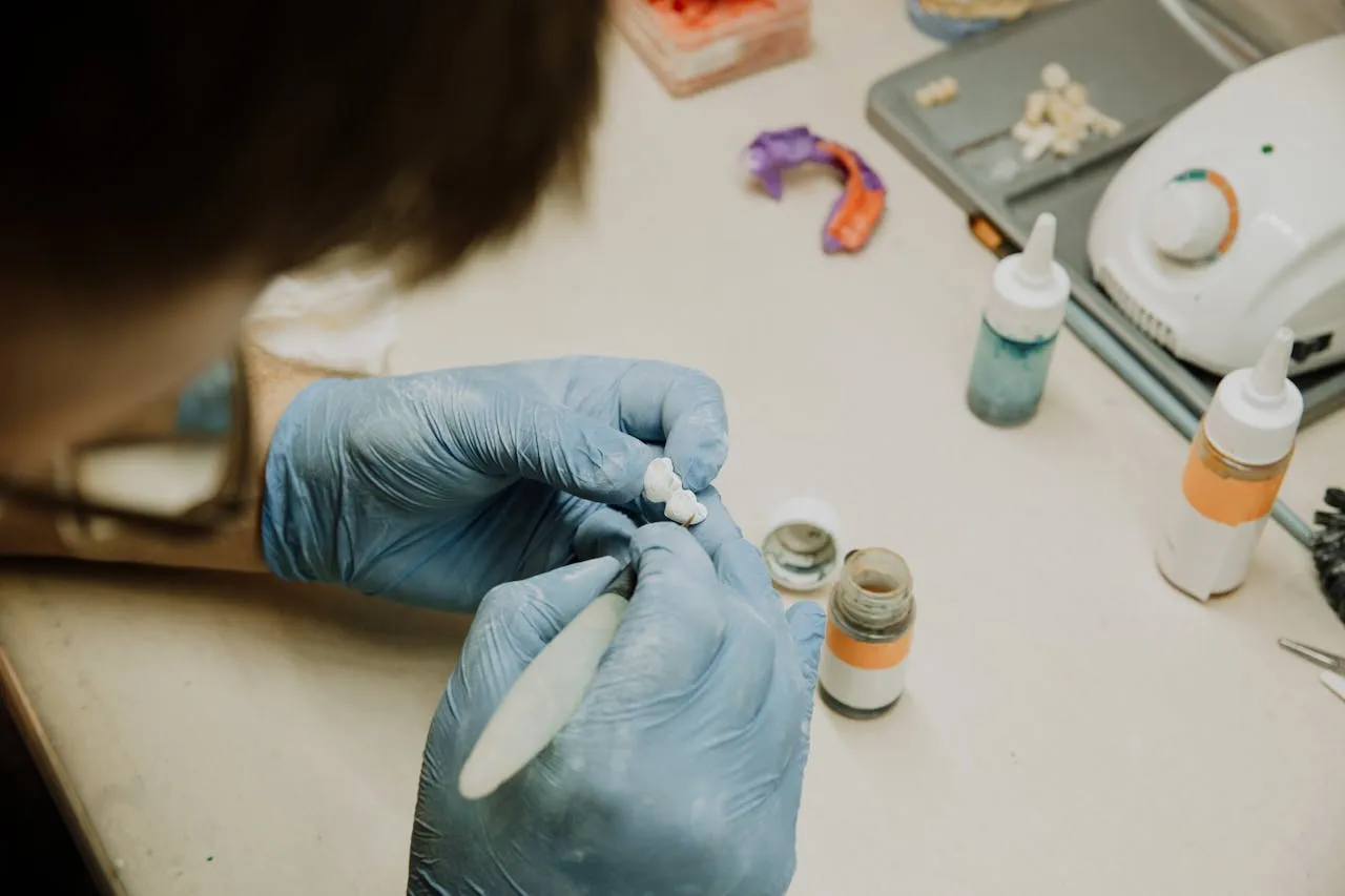Dental laboratory technician hand-crafting a prosthetic restoration — in-house lab craftsmanship behind crowns, bridges and veneers at top Turkish clinics