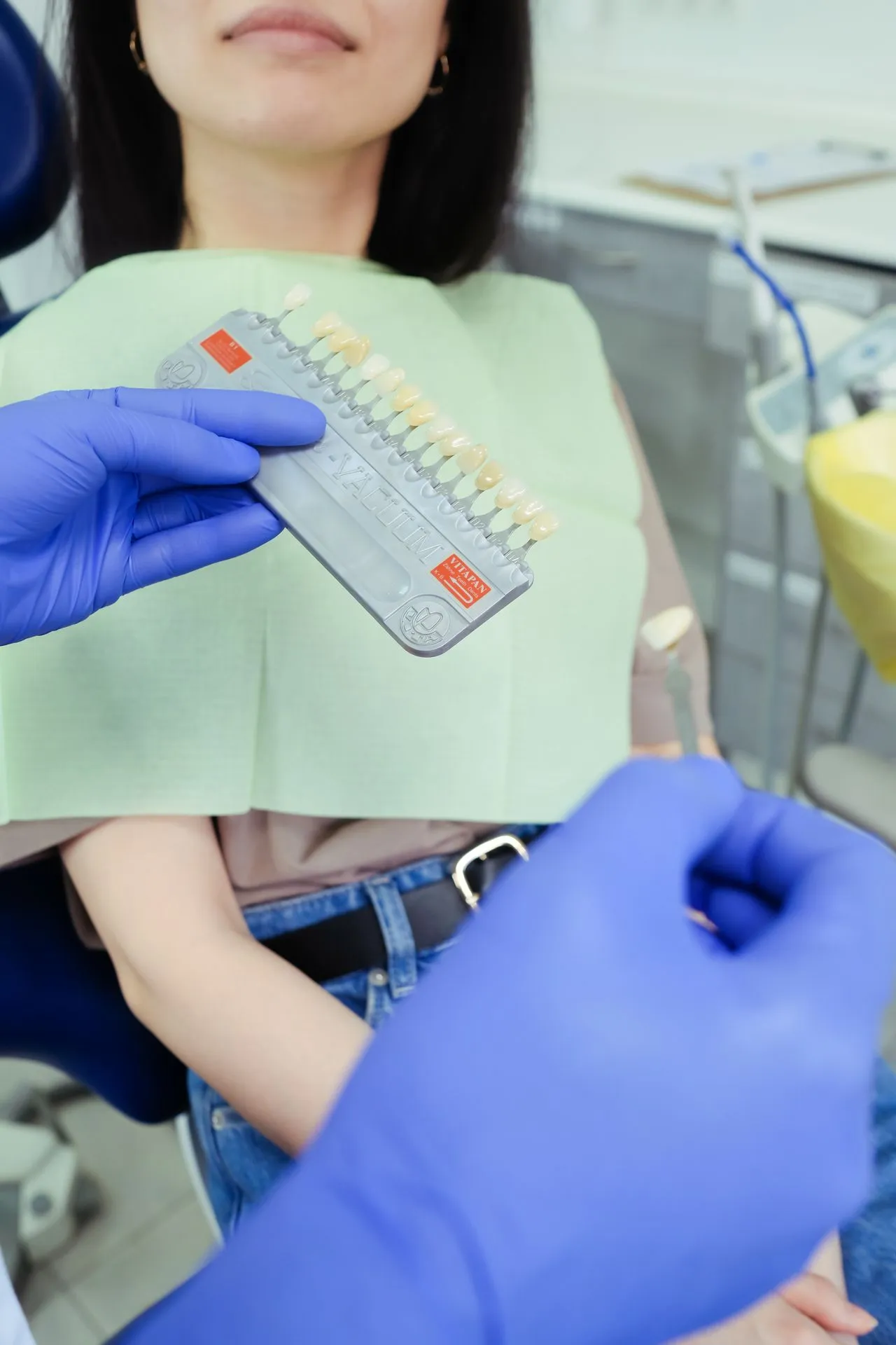 Dentist performing shade consultation before teeth whitening treatment — assessing baseline tooth colour